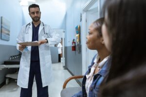 Médico em consulta com pacientes em clínica de cirurgia plástica, destacando um ambiente profissional e organizado.