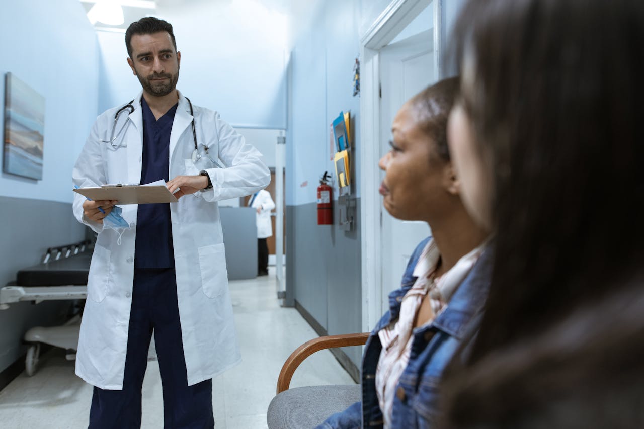 Médico em consulta com pacientes em clínica de cirurgia plástica, destacando um ambiente profissional e organizado.